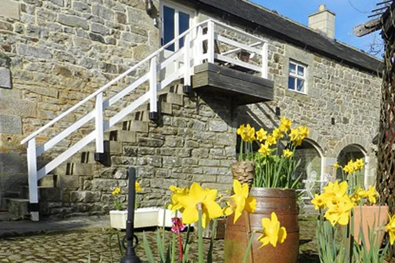 Stone coach house with steps leading to top floor entrance.