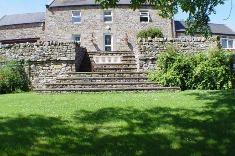Large stone house with tiered front garden.