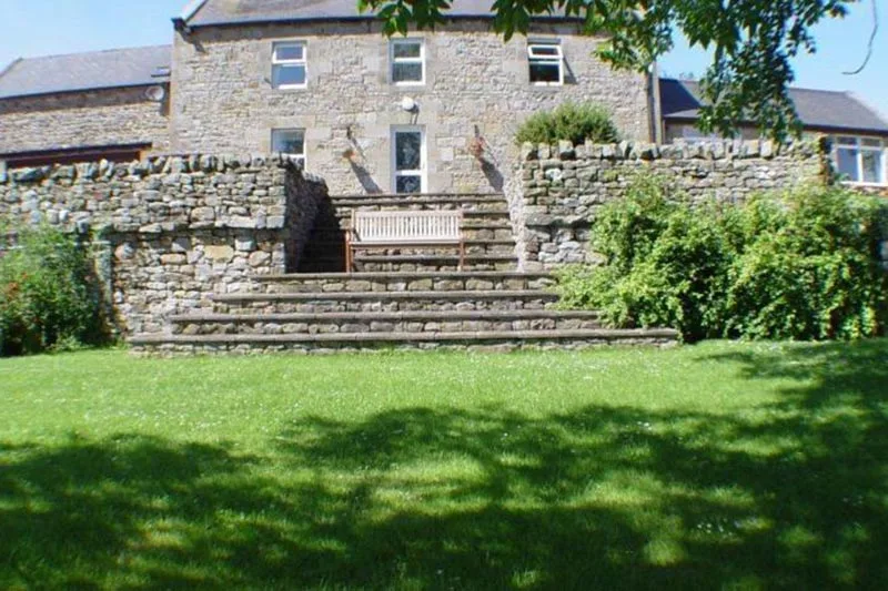 Large stone house with tiered front garden.